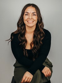 a smiling woman sitting on a stool